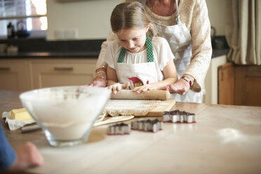 Senior woman and granddaughter rolling dough for Christmas tree cookies - CUF04377