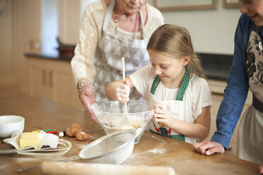 Senior woman and granddaughters stirring cookie mixture in bowl - CUF04379