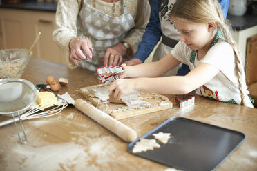 Cropped shot of senior woman and granddaughters cutting Christmas tree cookies at kitchen counter - CUF04381