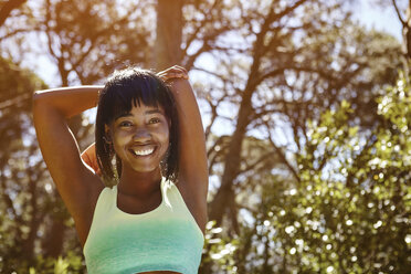 Portrait of young woman in rural setting, exercising, stretching arms - CUF04444