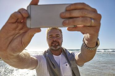 Älterer Mann am Strand, der ein Selfie mit seinem Smartphone macht, Kapstadt, Südafrika - CUF04456