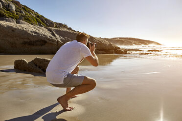Älterer Mann hockt am Strand und fotografiert die Aussicht, Kapstadt, Südafrika - CUF04458