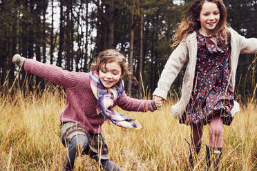 Two young girls running through meadow, hand in hand - CUF04466