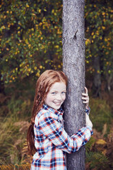 Portrait of young girl, hugging tree, smiling - CUF04483