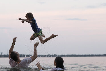 Bekleidete Eltern im Wasser, die ihren Sohn in die Luft werfen, Destin, Florida, Vereinigte Staaten, Nordamerika - ISF00944