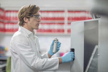 Male worker in thread factory, placing lab samples in chemical oven - ISF00983