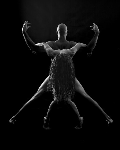 Paar in Yoga-Pose, schwarzer Hintergrund, lizenzfreies Stockfoto