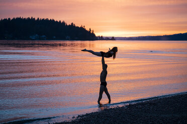 Ehepaar übt Yoga am Strand bei Sonnenuntergang - ISF00996