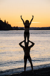 Couple practising yoga on beach at sunset - ISF00998