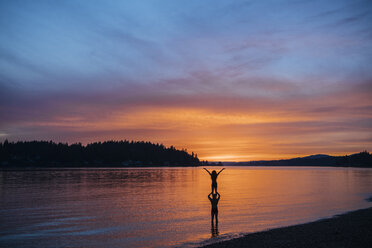 Couple practising yoga on beach at sunset - ISF01001