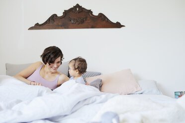 Mother sitting in bed with baby girl, smiling - ISF01019
