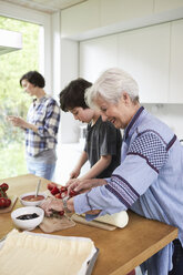 Großmutter und Enkel bereiten Essen in der Küche zu, Mutter im Hintergrund - ISF01051