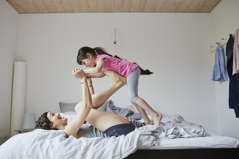 Mutter und Tochter spielen im Schlafzimmer, Mutter balanciert Tochter auf den Füßen - ISF01062