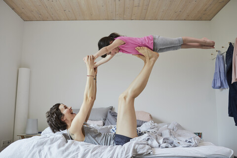 Mother and daughter playing in bedroom, mother balancing daughter on feet stock photo