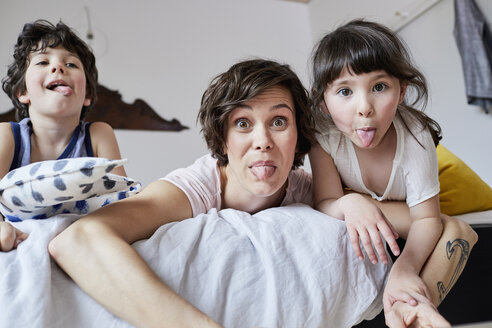 Porträt von Mutter, Sohn und Tochter, auf dem Bett liegend, die Zunge herausstreckend - ISF01078