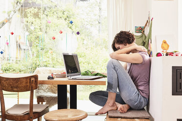 Mid adult woman at home, using laptop, worried expression - ISF01097