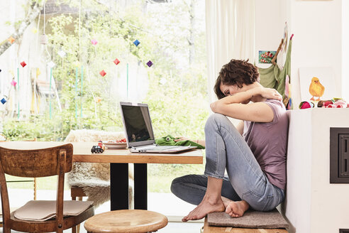 Mittlere erwachsene Frau zu Hause, mit Laptop, besorgter Gesichtsausdruck - ISF01097