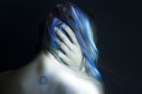 Rückansicht einer Frau mit der Hand in ihrem blauen Haar, Low-Key-Studioaufnahme - ISF01132