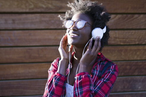 Porträt einer lächelnden jungen Frau, die mit Kopfhörern Musik hört - JSRF00044
