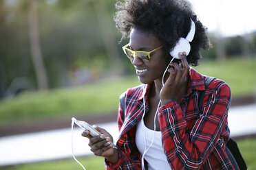 Portrait of happy young woman listening music with headphones and smartphone - JSRF00045