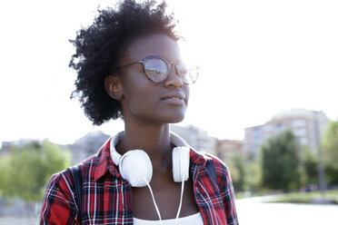Porträt einer jungen Frau mit Kopfhörern im Gegenlicht - JSRF00056