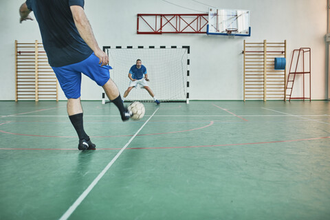 Zwei Männer spielen Hallenfußball und schießen auf ein Tor, lizenzfreies Stockfoto