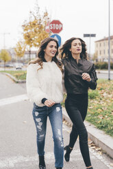 Zwillingsschwestern gehen lächelnd im Freien spazieren - CUF04516