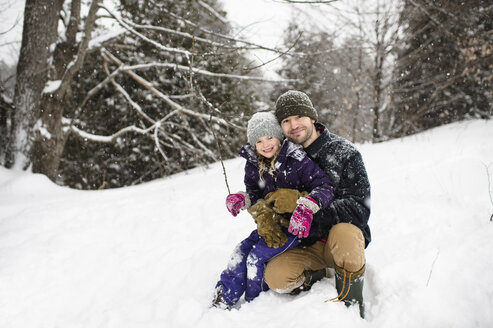 Porträt eines erwachsenen Mannes, der im Schnee hockt und seine Tochter umarmt - CUF04534