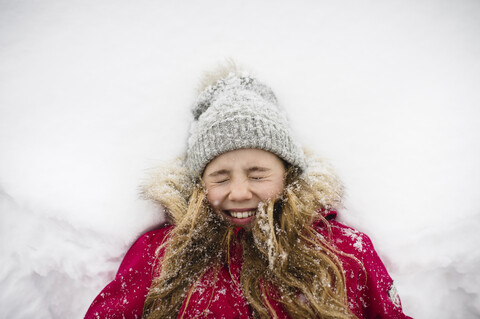 Mädchen auf dem Rücken liegend im Schnee mit geschlossenen Augen, lizenzfreies Stockfoto