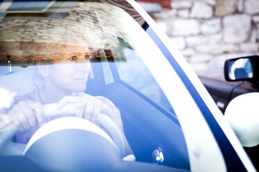 Smiling mature woman looking through car windscreen - CUF04599