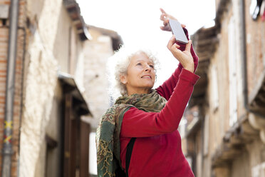 Woman taking photograph in street, Bruniquel, France - CUF04612
