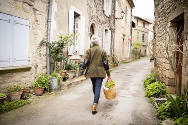 Rückansicht einer Frau, die in einer engen ländlichen Straße geht, Bruniquel, Frankreich - CUF04630