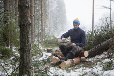 Holzfäller macht Pause auf Baumstämmen, Tammela, Forssa, Finnland - CUF04660