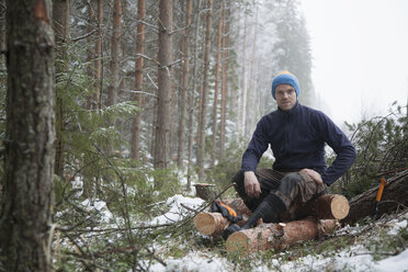 Holzfäller macht Pause auf Baumstämmen, Tammela, Forssa, Finnland - CUF04661