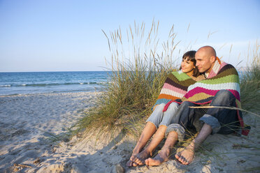 Couple covered with blanket on sand dune, Mallorca, Spain - CUF04666