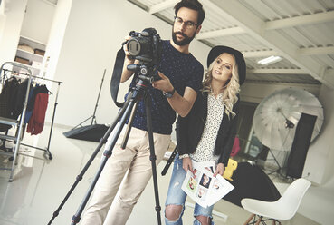 Photographers mounting camera on tripod in photography studio - CUF04702