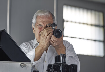 Senior man looking through camera - CUF04708