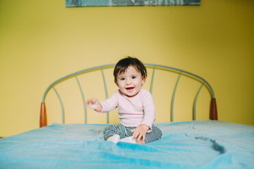 Happy baby girl sitting on the bed at home - GEMF01966