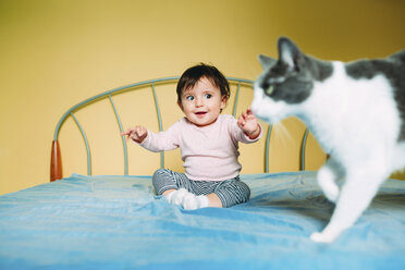 Überraschtes kleines Mädchen mit Katze auf dem Bett - GEMF01967