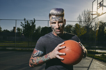 Porträt eines tätowierten jungen Mannes mit Basketball auf dem Platz - ZEDF01430