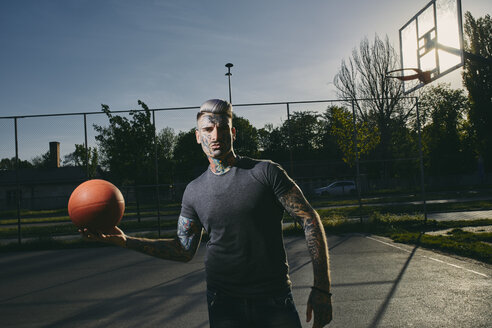 Porträt eines tätowierten jungen Mannes mit Basketball auf dem Platz - ZEDF01433