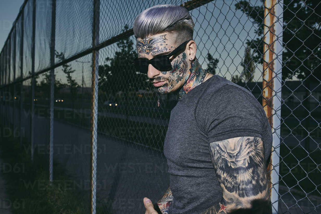 Informal tattooed man sitting near fence - a Royalty Free Stock Photo from  Photocase