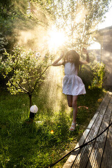 Mädchen hat Spaß mit Gartenschlauch im Sommer - SARF03735