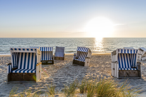 Deutschland, Schleswig-Holstein, Sylt, Strand und leere Strandkörbe mit Kapuze bei Sonnenuntergang, lizenzfreies Stockfoto