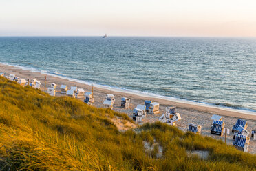 Germany, Schleswig-Holstein, Sylt, beach and empty hooded beach chairs at sunset - EGBF00249