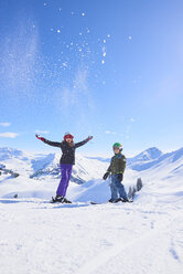 Porträt eines skifahrenden Teenagers und seines Bruders beim Pulverschnee werfen in den Schweizer Alpen, Gstaad, Schweiz - CUF04756