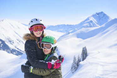 Porträt eines jugendlichen Mädchens beim Skifahren und eines Bruders, die sich in den Schweizer Alpen umarmen, Gstaad, Schweiz - CUF04757