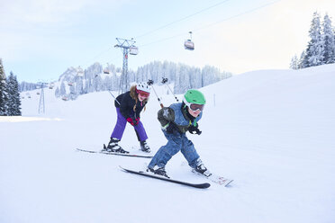 Teenage girl and brother skiing down ski slope, Gstaad, Switzerland - CUF04760