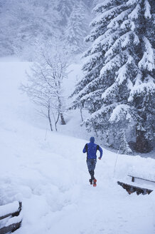 Rückansicht eines männlichen Läufers, der im Tiefschnee auf einer Bahn läuft, Gstaad, Schweiz - CUF04765