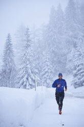 Männlicher Läufer beim Laufen im fallenden Schnee, Gstaad, Schweiz - CUF04771